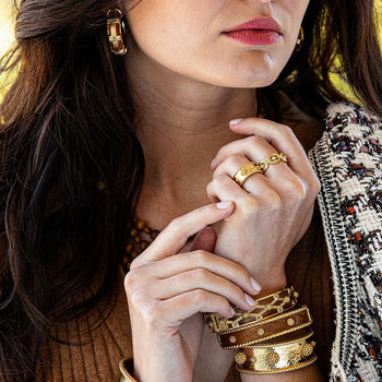 Teak and gold bracelets grace the wrists of a stoic model.