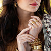 Teak and gold bracelets grace the wrists of a stoic model.