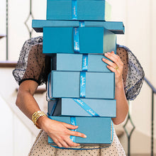 Woman holding 7 gift boxes stacked on eachother